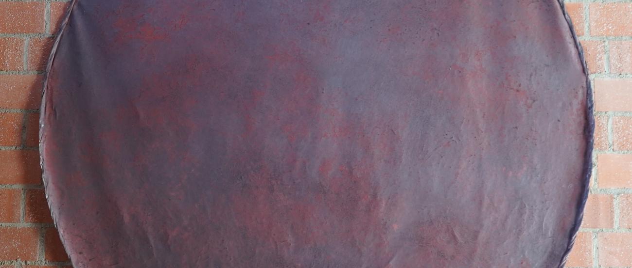 Rotbraun schimmerndes Kreisbild vor roter Backsteinwand