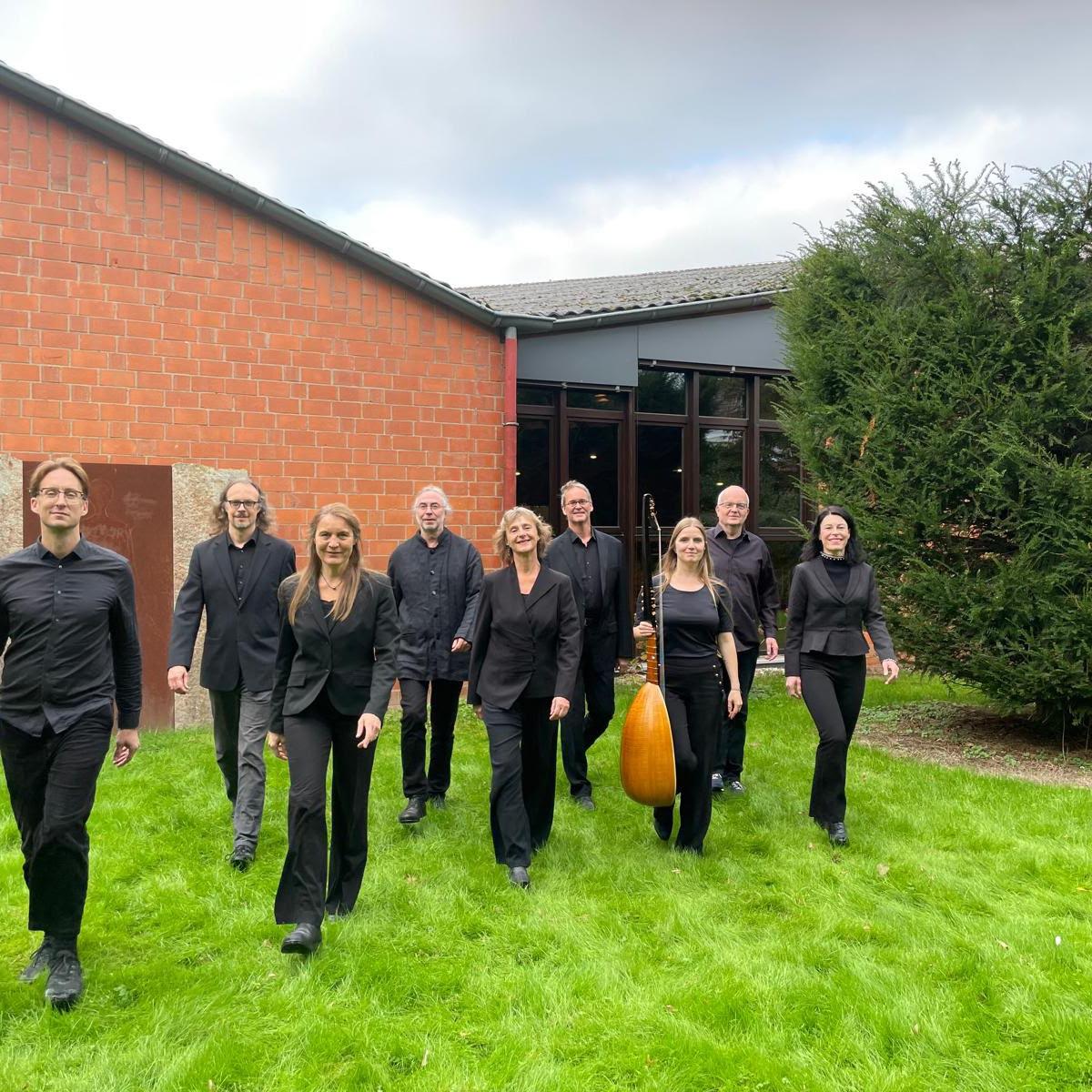 Mehrere Personen in schwarzer Kleidung laufen auf den Fotografen zu, einige von ihnen tragen Musikinstrumente bei sich. Im Hintergrund Pax Christi.