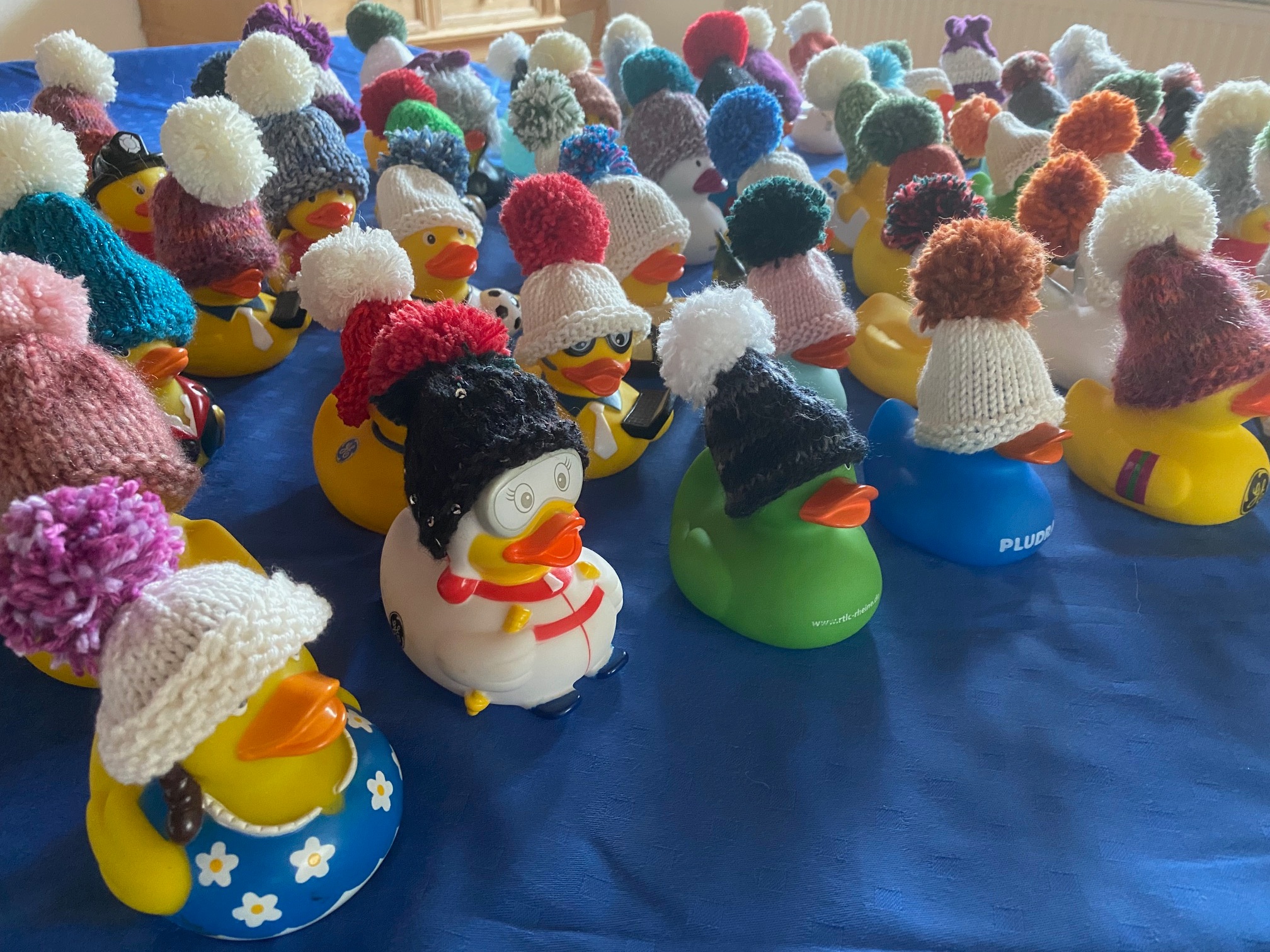 bunte Badeentchen, die kleine, gestrickte Mützen in verschiedenen Formen und Farben tragen