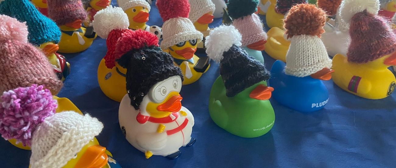 bunte Badeentchen, die kleine, gestrickte Mützen in verschiedenen Formen und Farben tragen