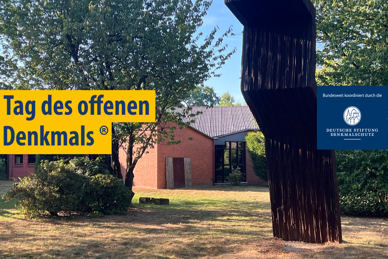 Skulptur aus dunklem Material vor einem roten Backsteingebäude mit Bäumen und gelbem Schriftzug 'Tag des offenen Denkmals (R)' sowie blauem Einstecker mit 'bundesweit koordiniert durch die Deutsche Stiftung Denkmalschutz'.