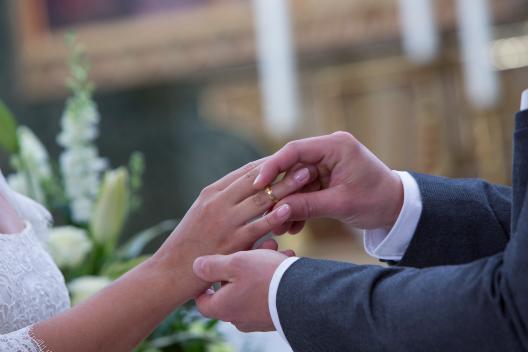 Braut und Bräutigam stecken sich gegenseitig die Ringe an.