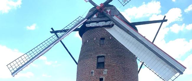 Die Geismühle Krefeld Oppum, im Hintergrund hellblauer Himmel und weiße Wolken.
