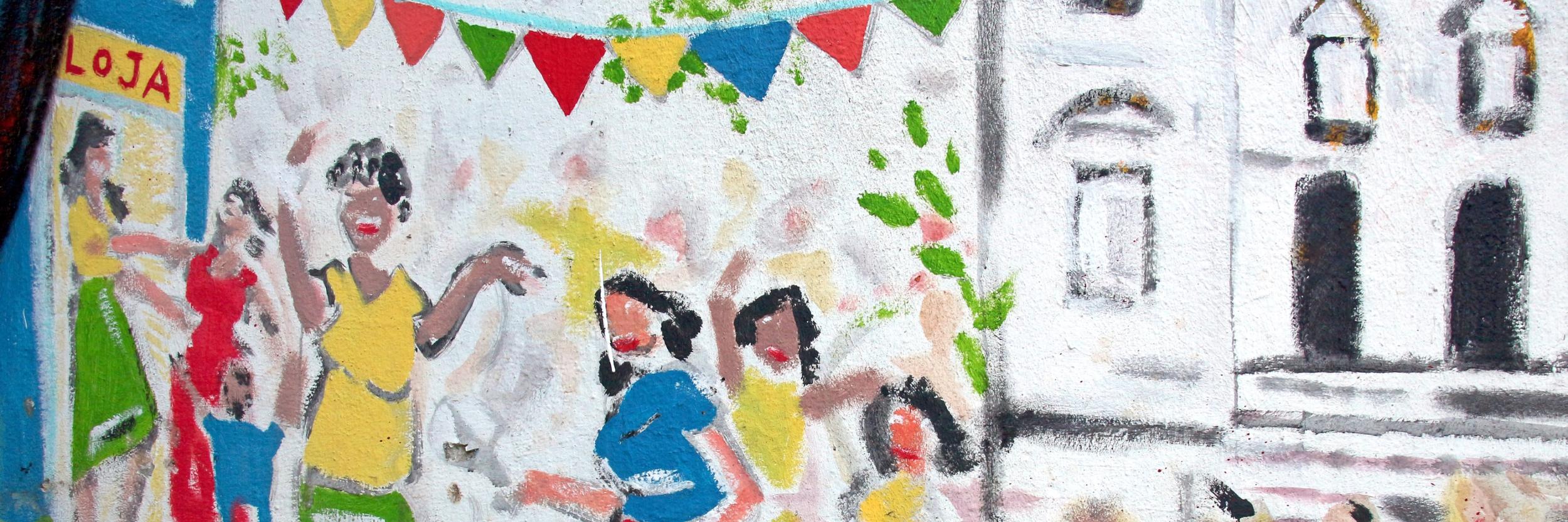 Buntes Wandgemälde mit tanzenden Menschen und fröhlichen Festtagsfahnen.