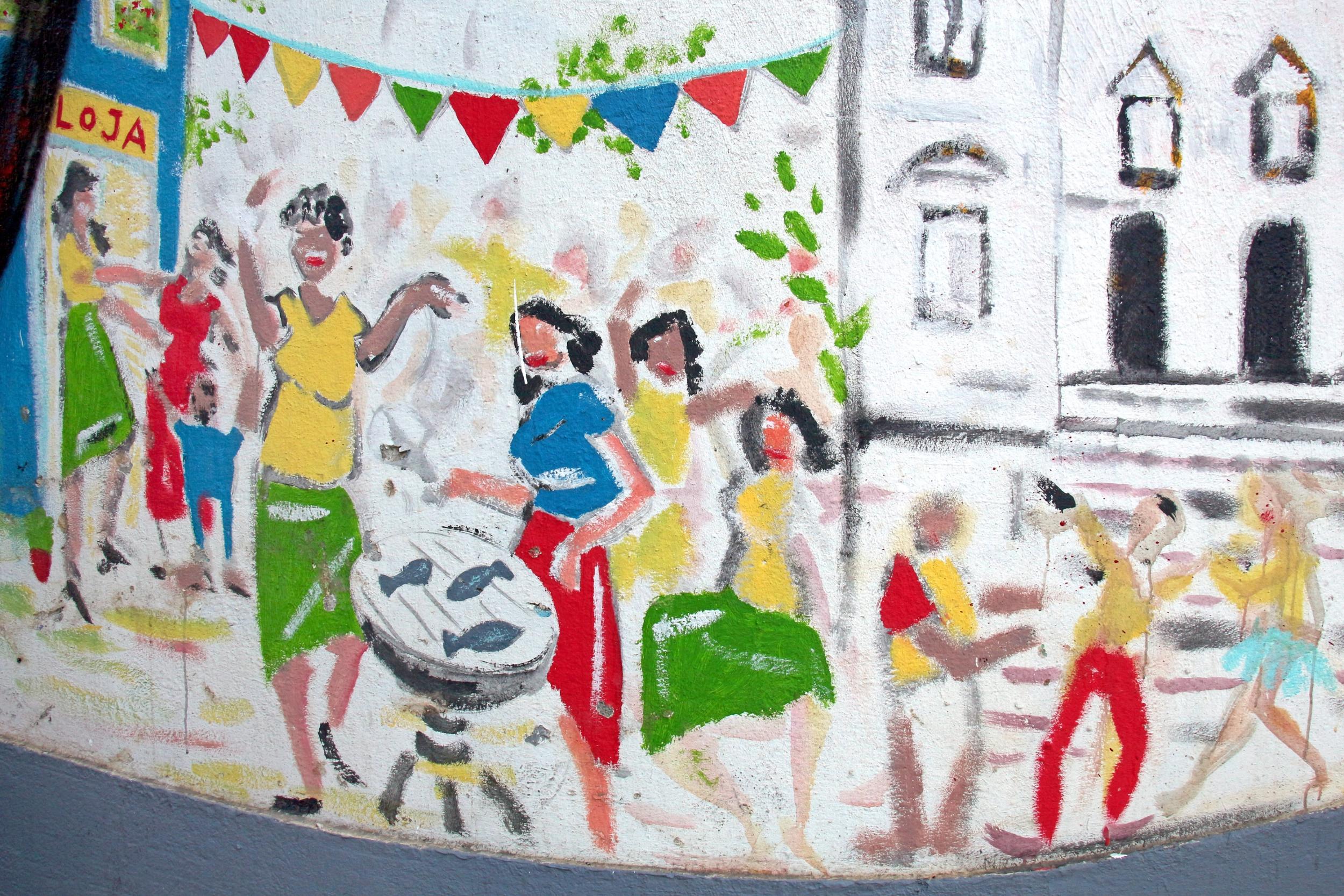 Buntes Wandgemälde mit tanzenden Menschen und fröhlichen Festtagsfahnen.